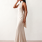 Woman wearing the Winnie satin halter maxi dress featuring a glossy satin finish, halter neckline with tie-back detail, open draped back, and a floor-length relaxed silhouette.