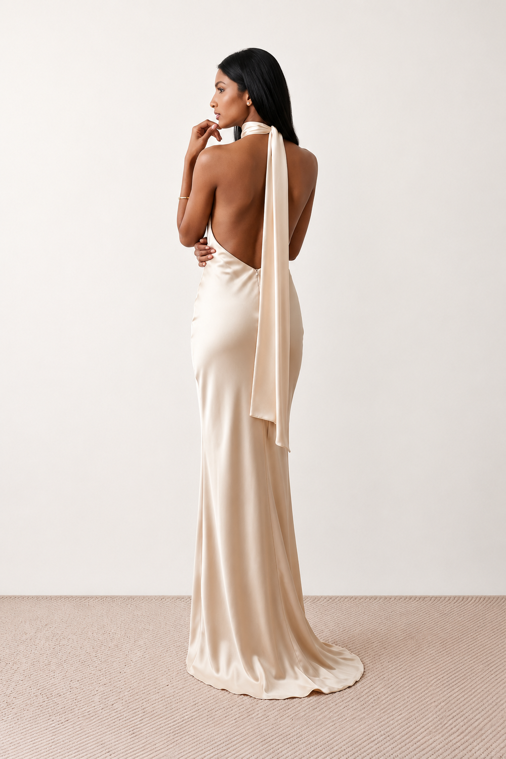 Woman wearing the Winnie satin halter maxi dress featuring a glossy satin finish, halter neckline with tie-back detail, open draped back, and a floor-length relaxed silhouette.