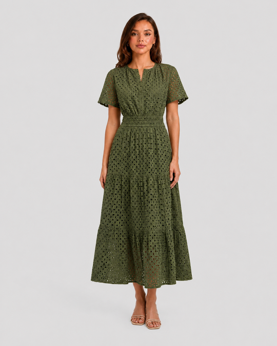 Woman wearing a white eyelet A-line midi dress with a softly defined waist, tiered skirt, and breathable cotton-blend fabric for summer occasions.