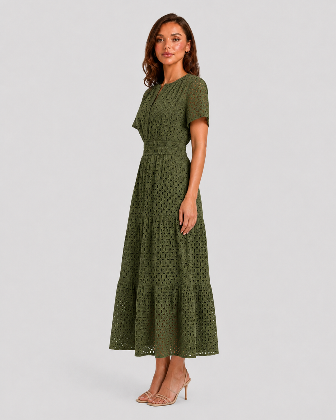 Woman wearing a white eyelet A-line midi dress with a softly defined waist, tiered skirt, and breathable cotton-blend fabric for summer occasions.