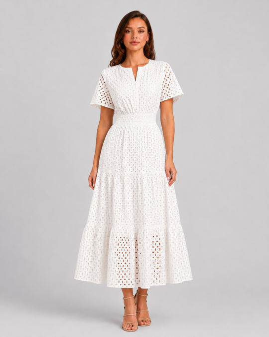 Woman wearing a white eyelet A-line midi dress with a softly defined waist, tiered skirt, and breathable cotton-blend fabric for summer occasions.