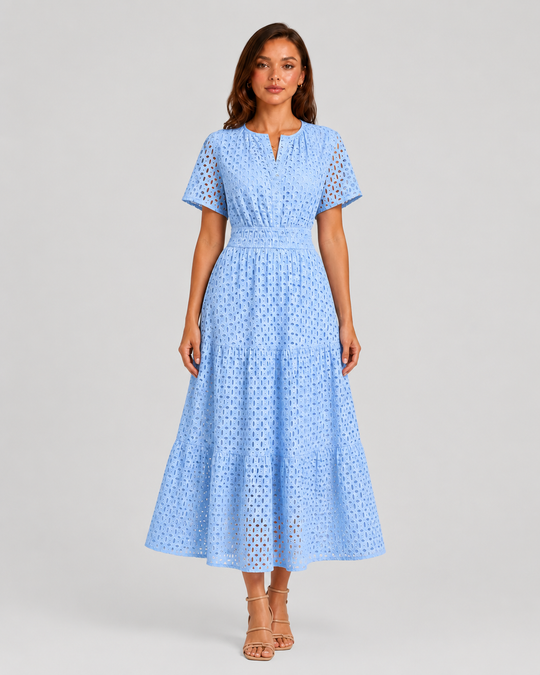 Woman wearing a white eyelet A-line midi dress with a softly defined waist, tiered skirt, and breathable cotton-blend fabric for summer occasions.