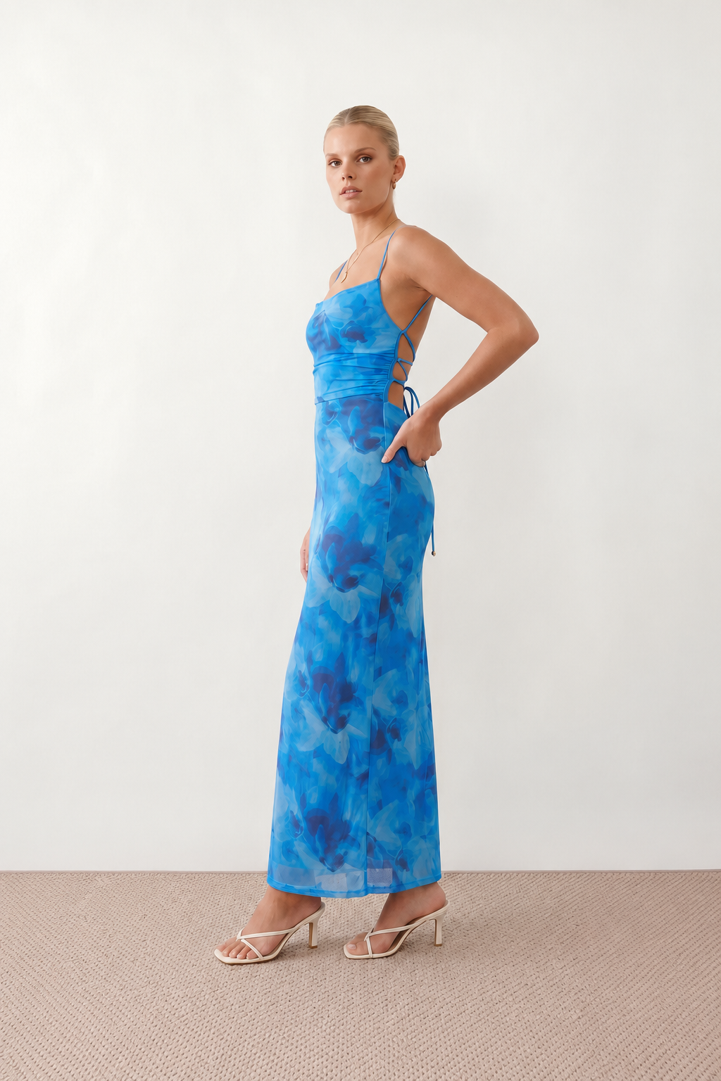 Seren spaghetti strap maxi dress in an abstract floral print featuring a square neckline, thin straps, a low lace-up open back, a shirred waist, and a fitted floor-length silhouette.
