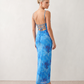 Seren spaghetti strap maxi dress in an abstract floral print featuring a square neckline, thin straps, a low lace-up open back, a shirred waist, and a fitted floor-length silhouette.