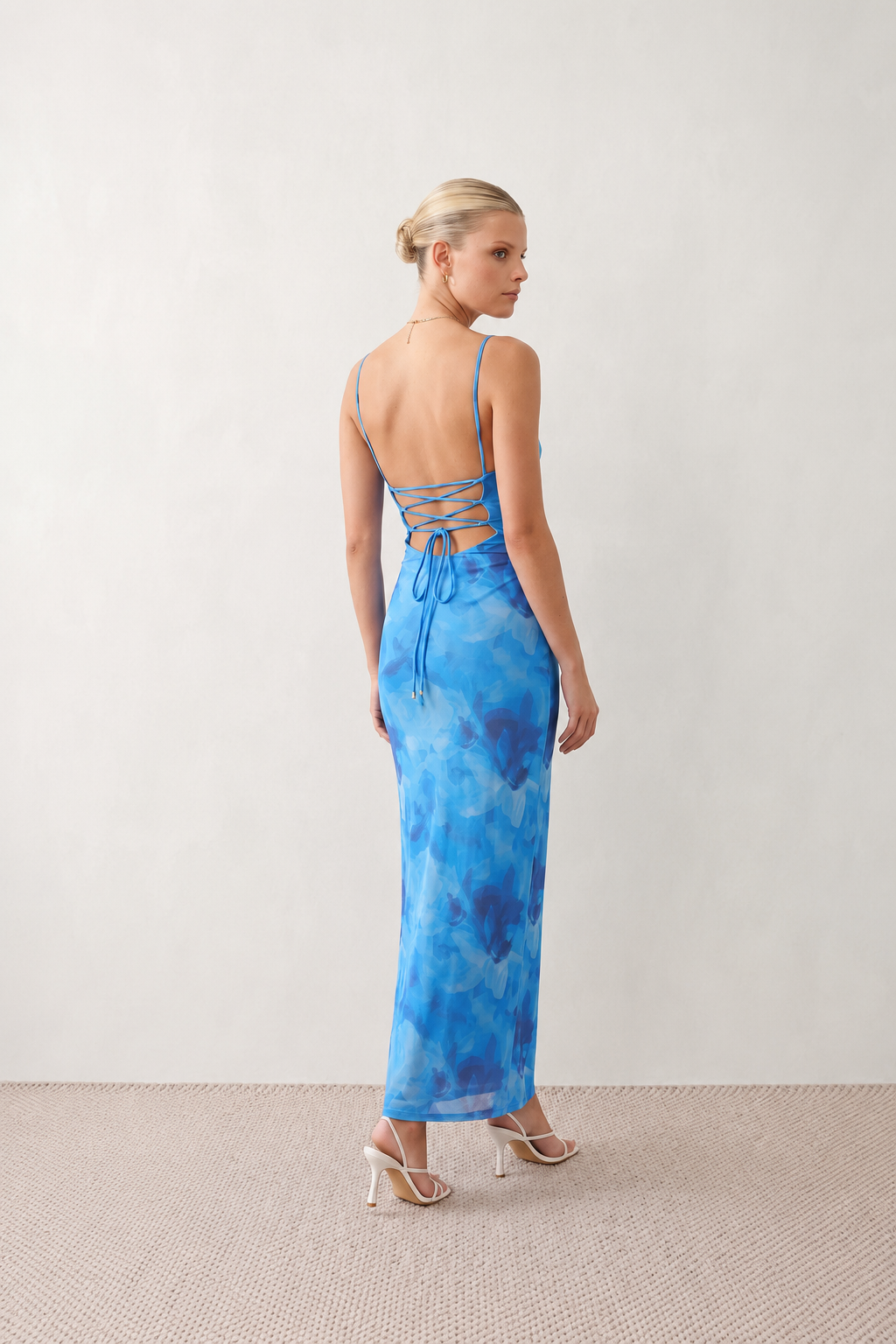 Seren spaghetti strap maxi dress in an abstract floral print featuring a square neckline, thin straps, a low lace-up open back, a shirred waist, and a fitted floor-length silhouette.