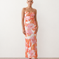 Seren spaghetti strap maxi dress in an abstract floral print featuring a square neckline, thin straps, a low lace-up open back, a shirred waist, and a fitted floor-length silhouette.