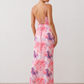 Seren spaghetti strap maxi dress in an abstract floral print featuring a square neckline, thin straps, a low lace-up open back, a shirred waist, and a fitted floor-length silhouette.