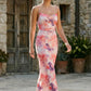 Seren spaghetti strap maxi dress in an abstract floral print featuring a square neckline, thin straps, a low lace-up open back, a shirred waist, and a fitted floor-length silhouette.