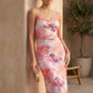 Seren spaghetti strap maxi dress in an abstract floral print featuring a square neckline, thin straps, a low lace-up open back, a shirred waist, and a fitted floor-length silhouette.