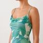 Seren spaghetti strap maxi dress in an abstract floral print featuring a square neckline, thin straps, a low lace-up open back, a shirred waist, and a fitted floor-length silhouette.