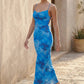 Seren spaghetti strap maxi dress in an abstract floral print featuring a square neckline, thin straps, a low lace-up open back, a shirred waist, and a fitted floor-length silhouette.