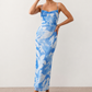 Seren spaghetti strap maxi dress in an abstract floral print featuring a square neckline, thin straps, a low lace-up open back, a shirred waist, and a fitted floor-length silhouette.