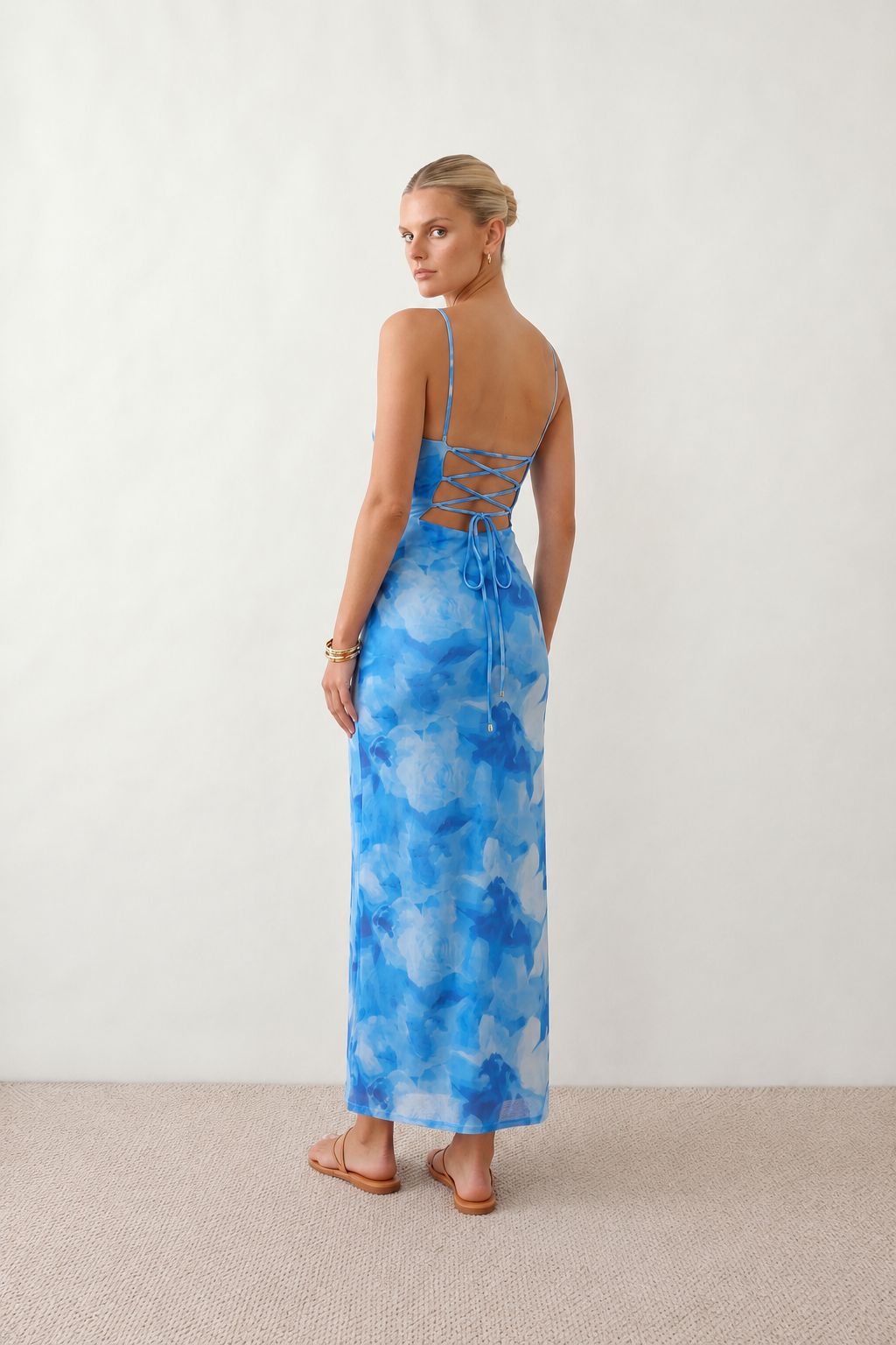 Seren spaghetti strap maxi dress in an abstract floral print featuring a square neckline, thin straps, a low lace-up open back, a shirred waist, and a fitted floor-length silhouette.
