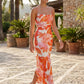 Seren spaghetti strap maxi dress in an abstract floral print featuring a square neckline, thin straps, a low lace-up open back, a shirred waist, and a fitted floor-length silhouette.