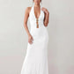 Woman wearing the Ariadna Mermaid Halter Maxi Dress featuring a deep plunge halter neckline, open back with adjustable tie fastening, gold-tone hardware at the ruched waist, subtle waist cut-out and a floor-length mermaid silhouette, ideal for weddings, black-tie events and formal evening occasions.