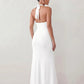 Woman wearing the Ariadna Mermaid Halter Maxi Dress featuring a deep plunge halter neckline, open back with adjustable tie fastening, gold-tone hardware at the ruched waist, subtle waist cut-out and a floor-length mermaid silhouette, ideal for weddings, black-tie events and formal evening occasions.