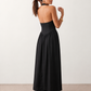 Aurora basque waist halter maxi dress with a halter neckline, open back, defined basque waist, and flowing A-line skirt in smooth fabric, ideal for weddings, formal events, and evening occasions.