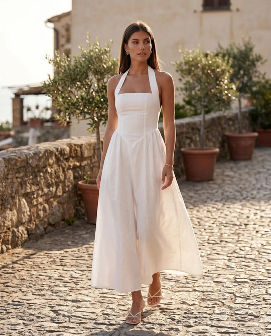 Aurora basque waist halter maxi dress with a halter neckline, open back, defined basque waist, and flowing A-line skirt in smooth fabric, ideal for weddings, formal events, and evening occasions.