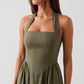 Aurora basque waist halter maxi dress with a halter neckline, open back, defined basque waist, and flowing A-line skirt in smooth fabric, ideal for weddings, formal events, and evening occasions.