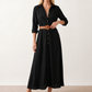 Woman wearing the Julieta Button Front Maxi Dress with a deep V-neck, shirt collar, button-front bodice, long sleeves, belted waist with a square-buckle belt, asymmetric pleated hip drape, and flowing maxi-length skirt.