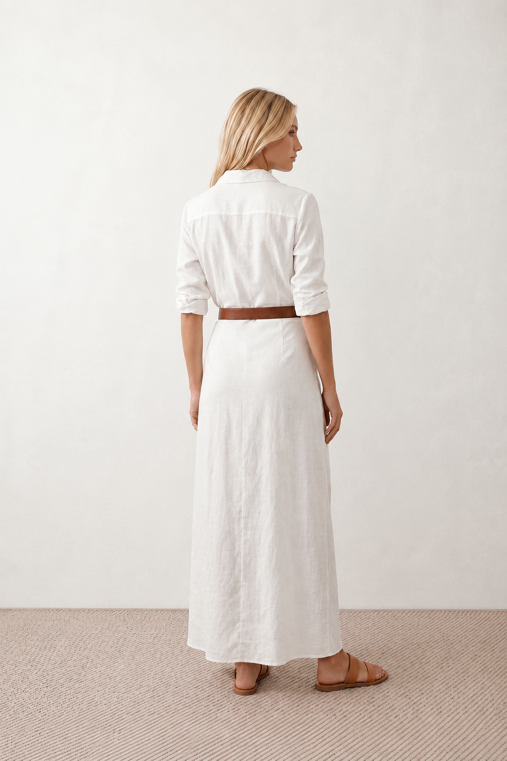 Woman wearing the Julieta Button Front Maxi Dress with a deep V-neck, shirt collar, button-front bodice, long sleeves, belted waist with a square-buckle belt, asymmetric pleated hip drape, and flowing maxi-length skirt.