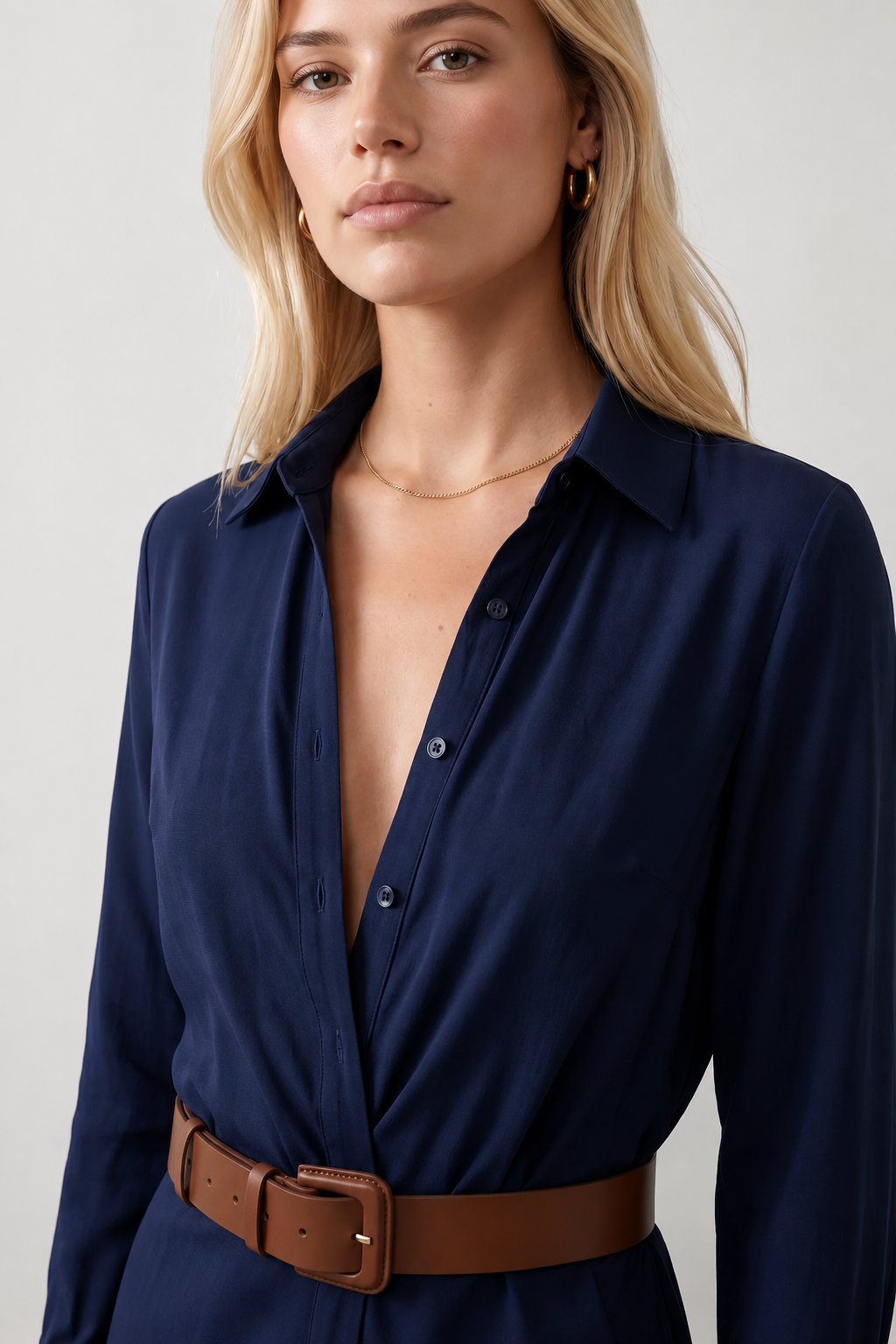 Woman wearing the Julieta Button Front Maxi Dress with a deep V-neck, shirt collar, button-front bodice, long sleeves, belted waist with a square-buckle belt, asymmetric pleated hip drape, and flowing maxi-length skirt.