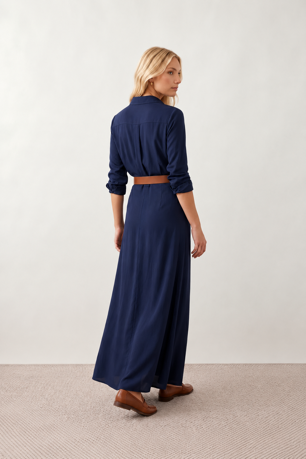 Woman wearing the Julieta Button Front Maxi Dress with a deep V-neck, shirt collar, button-front bodice, long sleeves, belted waist with a square-buckle belt, asymmetric pleated hip drape, and flowing maxi-length skirt.