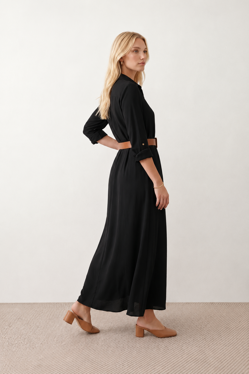 Woman wearing the Julieta Button Front Maxi Dress with a deep V-neck, shirt collar, button-front bodice, long sleeves, belted waist with a square-buckle belt, asymmetric pleated hip drape, and flowing maxi-length skirt.