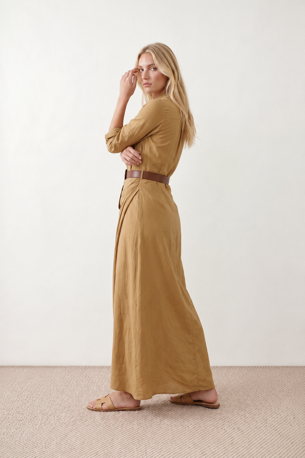 Woman wearing the Julieta Button Front Maxi Dress with a deep V-neck, shirt collar, button-front bodice, long sleeves, belted waist with a square-buckle belt, asymmetric pleated hip drape, and flowing maxi-length skirt.