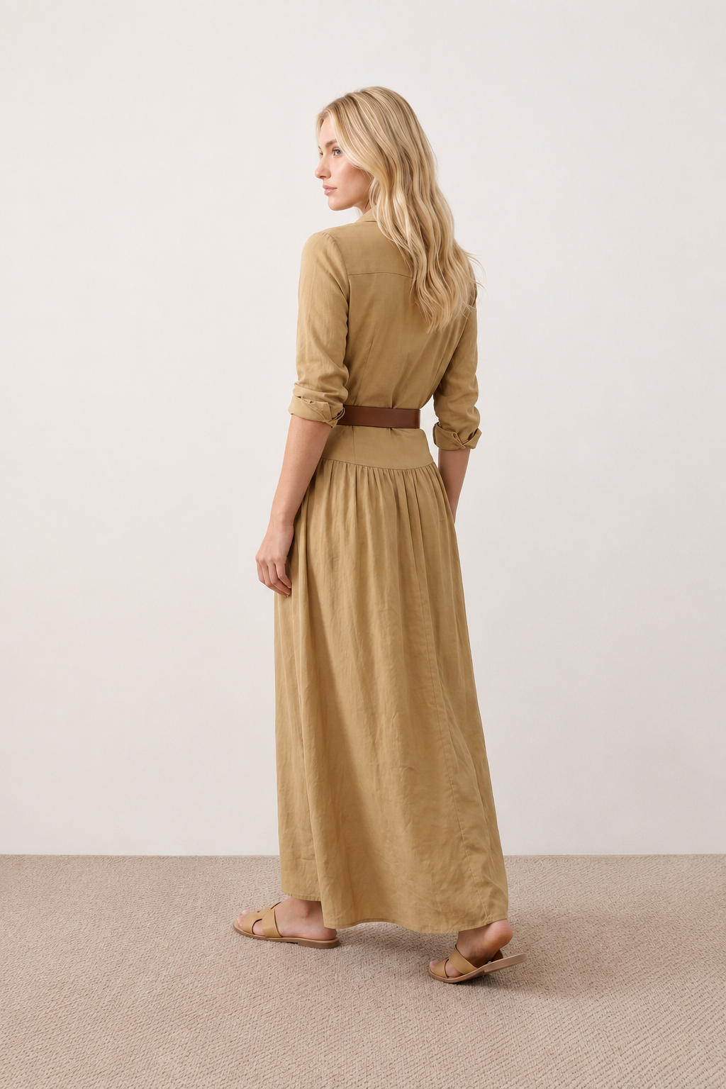 Woman wearing the Julieta Button Front Maxi Dress with a deep V-neck, shirt collar, button-front bodice, long sleeves, belted waist with a square-buckle belt, asymmetric pleated hip drape, and flowing maxi-length skirt.