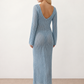 Woman wearing the Calixta Crochet Plunge Neck Maxi Dress in an elegant open-knit crochet design with a deep plunge V-neck, keyhole detail, long flared sleeves, low open back and fitted floor-length silhouette, ideal for beach holidays, festivals and summer occasion wear.