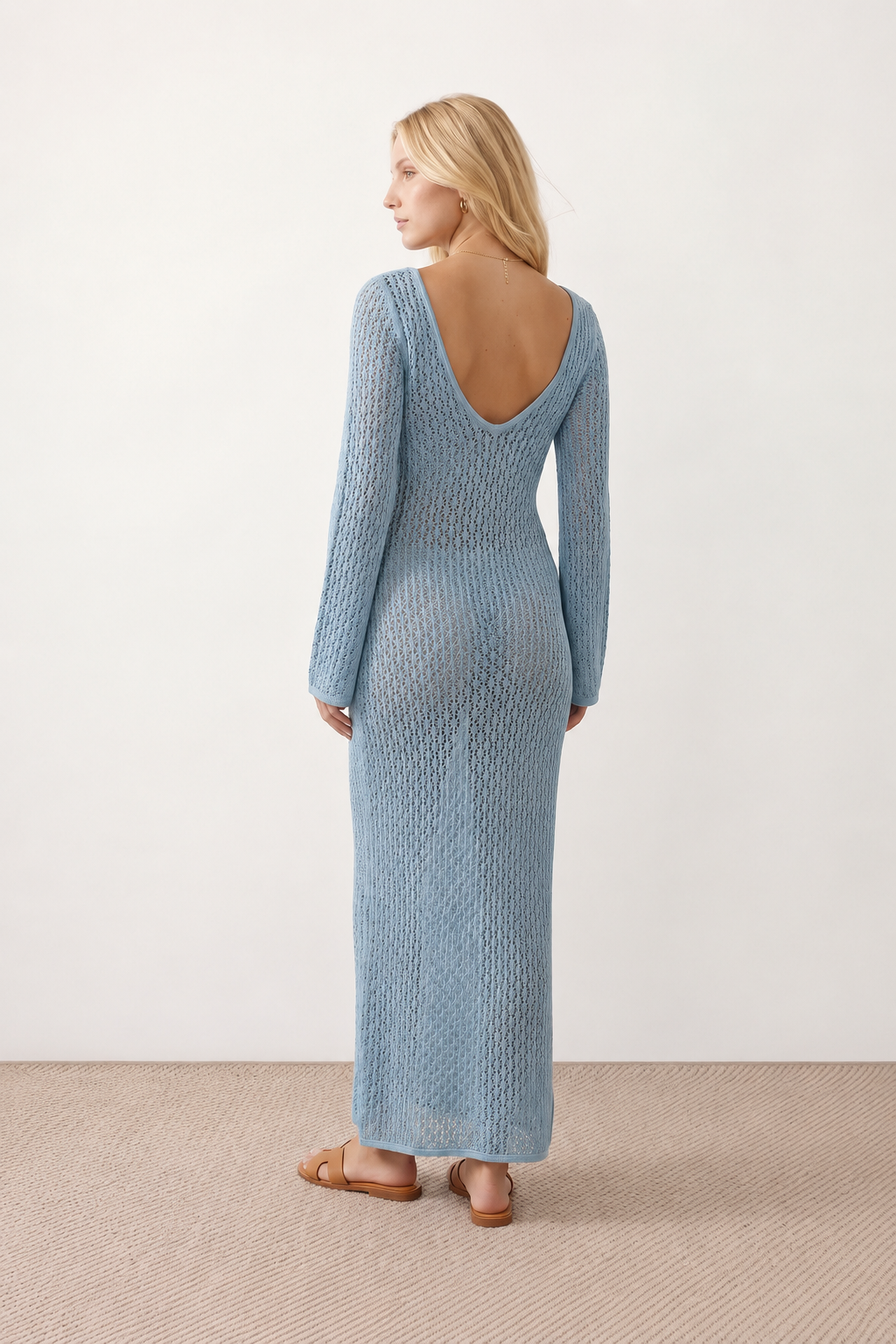 Woman wearing the Calixta Crochet Plunge Neck Maxi Dress in an elegant open-knit crochet design with a deep plunge V-neck, keyhole detail, long flared sleeves, low open back and fitted floor-length silhouette, ideal for beach holidays, festivals and summer occasion wear.