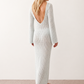 Woman wearing the Calixta Crochet Plunge Neck Maxi Dress in an elegant open-knit crochet design with a deep plunge V-neck, keyhole detail, long flared sleeves, low open back and fitted floor-length silhouette, ideal for beach holidays, festivals and summer occasion wear.