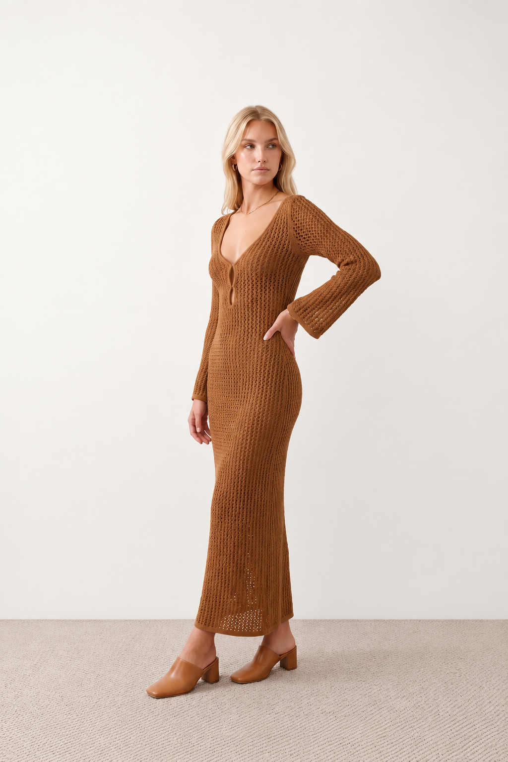 Woman wearing the Calixta Crochet Plunge Neck Maxi Dress in an elegant open-knit crochet design with a deep plunge V-neck, keyhole detail, long flared sleeves, low open back and fitted floor-length silhouette, ideal for beach holidays, festivals and summer occasion wear.