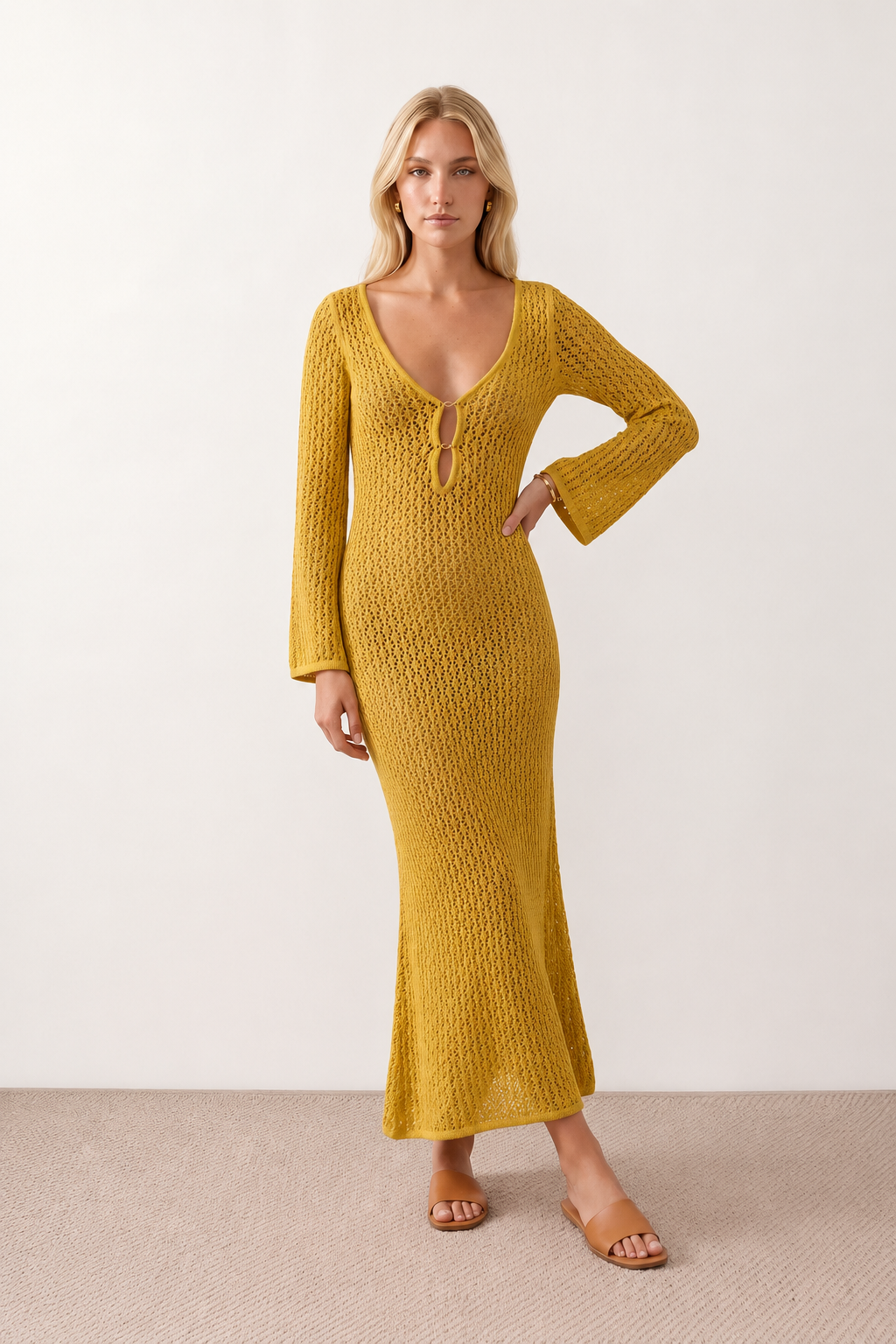 Woman wearing the Calixta Crochet Plunge Neck Maxi Dress in an elegant open-knit crochet design with a deep plunge V-neck, keyhole detail, long flared sleeves, low open back and fitted floor-length silhouette, ideal for beach holidays, festivals and summer occasion wear.