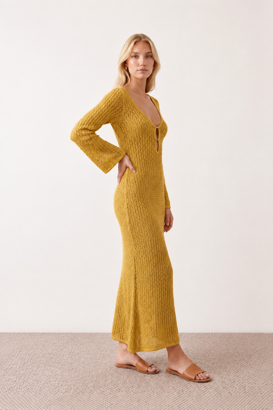 Woman wearing the Calixta Crochet Plunge Neck Maxi Dress in an elegant open-knit crochet design with a deep plunge V-neck, keyhole detail, long flared sleeves, low open back and fitted floor-length silhouette, ideal for beach holidays, festivals and summer occasion wear.