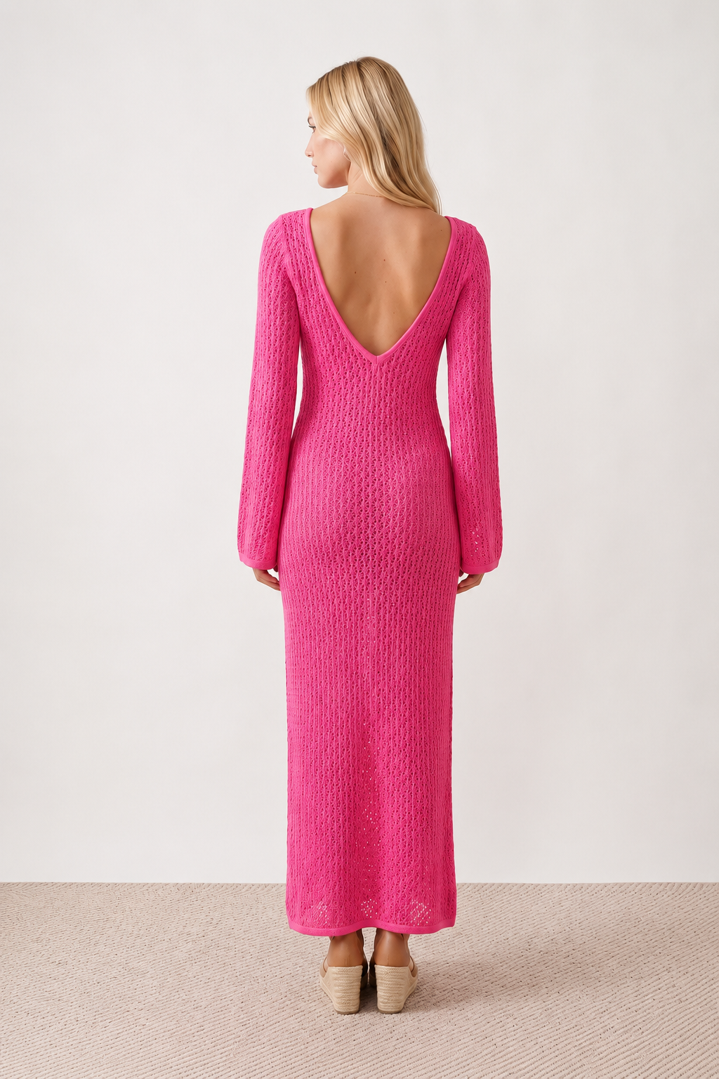 Woman wearing the Calixta Crochet Plunge Neck Maxi Dress in an elegant open-knit crochet design with a deep plunge V-neck, keyhole detail, long flared sleeves, low open back and fitted floor-length silhouette, ideal for beach holidays, festivals and summer occasion wear.