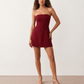 Woman wearing the Camilla Strapless Pleated Mini Dress featuring a structured strapless square neckline, fitted bodice, softly pleated A-line mini skirt, natural waist, and concealed back zip, styled for weddings, cocktail parties, race days, and special occasions.