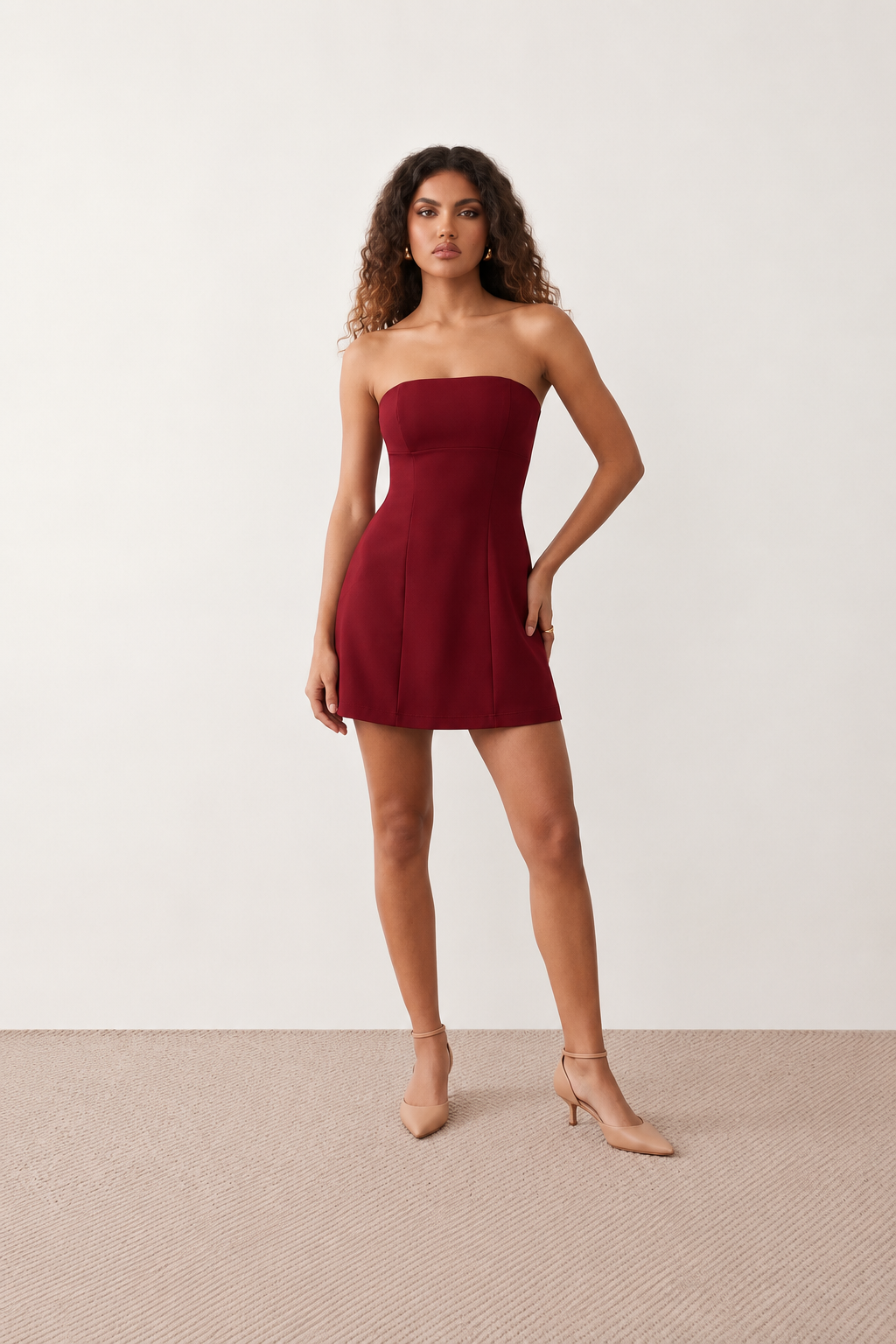 Woman wearing the Camilla Strapless Pleated Mini Dress featuring a structured strapless square neckline, fitted bodice, softly pleated A-line mini skirt, natural waist, and concealed back zip, styled for weddings, cocktail parties, race days, and special occasions.