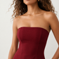 Woman wearing the Camilla Strapless Pleated Mini Dress featuring a structured strapless square neckline, fitted bodice, softly pleated A-line mini skirt, natural waist, and concealed back zip, styled for weddings, cocktail parties, race days, and special occasions.