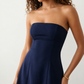 Woman wearing the Camilla Strapless Pleated Mini Dress featuring a structured strapless square neckline, fitted bodice, softly pleated A-line mini skirt, natural waist, and concealed back zip, styled for weddings, cocktail parties, race days, and special occasions.