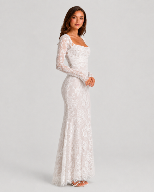 Woman wearing a lace corset maxi dress with a structured bodice, adjustable lace-up back, delicate lace detailing, and flowing floor-length silhouette.