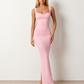 Woman wearing the Aline Cowl Neck Backless Maxi Dress in a floor-length fitted silhouette with a draped cowl neckline, elegant open back, oversized satin bow tie detail, sleeveless design, and smooth woven fabric, ideal for weddings, black-tie events, galas, and evening occasions.
