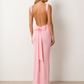 Woman wearing the Aline Cowl Neck Backless Maxi Dress in a floor-length fitted silhouette with a draped cowl neckline, elegant open back, oversized satin bow tie detail, sleeveless design, and smooth woven fabric, ideal for weddings, black-tie events, galas, and evening occasions.