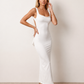 Woman wearing the Aline Cowl Neck Backless Maxi Dress in a floor-length fitted silhouette with a draped cowl neckline, elegant open back, oversized satin bow tie detail, sleeveless design, and smooth woven fabric, ideal for weddings, black-tie events, galas, and evening occasions.