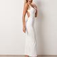 Woman wearing the Aline Cowl Neck Backless Maxi Dress in a floor-length fitted silhouette with a draped cowl neckline, elegant open back, oversized satin bow tie detail, sleeveless design, and smooth woven fabric, ideal for weddings, black-tie events, galas, and evening occasions.