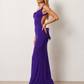 Woman wearing the Aline Cowl Neck Backless Maxi Dress in a floor-length fitted silhouette with a draped cowl neckline, elegant open back, oversized satin bow tie detail, sleeveless design, and smooth woven fabric, ideal for weddings, black-tie events, galas, and evening occasions.