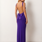 Woman wearing the Aline Cowl Neck Backless Maxi Dress in a floor-length fitted silhouette with a draped cowl neckline, elegant open back, oversized satin bow tie detail, sleeveless design, and smooth woven fabric, ideal for weddings, black-tie events, galas, and evening occasions.
