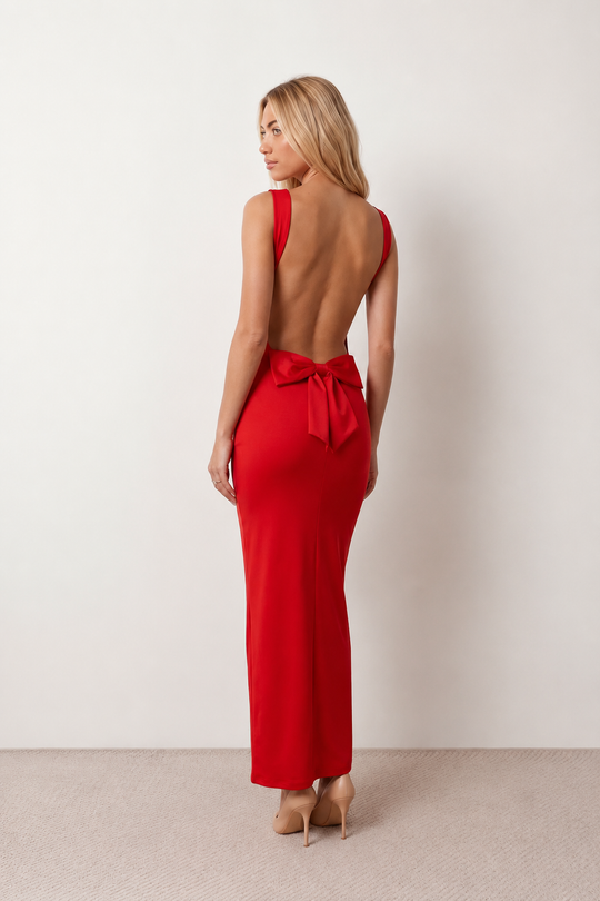 Woman wearing the Aline Cowl Neck Backless Maxi Dress in a floor-length fitted silhouette with a draped cowl neckline, elegant open back, oversized satin bow tie detail, sleeveless design, and smooth woven fabric, ideal for weddings, black-tie events, galas, and evening occasions.