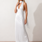 Aleena cowl neck halter maxi dress with a deep draped neckline, fitted halter strap, open back with tie-neck closure, sleeveless column silhouette, and floor-length straight hem in a smooth, elegant finish.